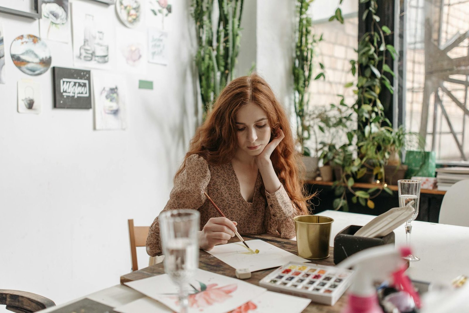 A young woman in a cozy art studio painting with watercolors on a sunny day.