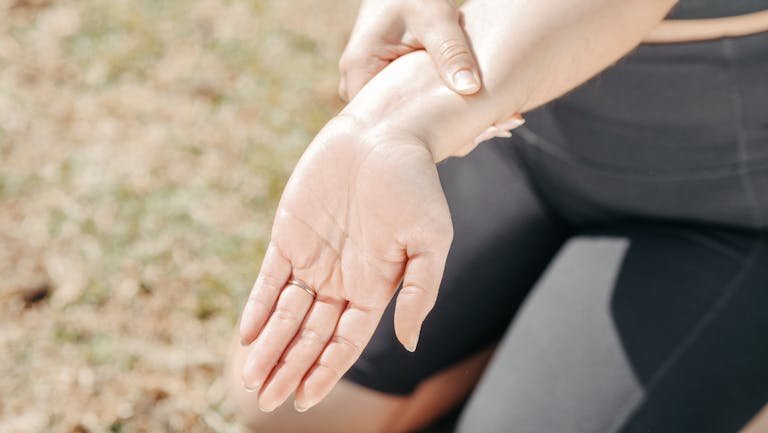 Woman holding her stiff hand in morning light – early RA signs”